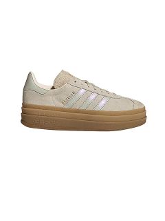 Zapatilla Adidas Gazelle beige con rayas blancas, letras doradas de "GAZELLE" y una suela de goma gruesa sobre un fondo blanco.