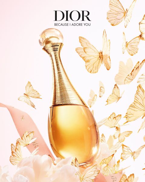 Un frasco dorado de perfume Dior, rodeado de mariposas doradas flotantes, lazo rosa y delicadas flores blancas con el texto "DIOR Because I Adore You".