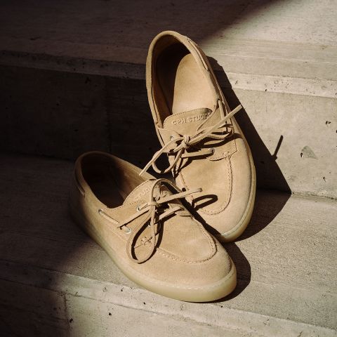 Náuticos de ante color beige con cordones sobre escalones de hormigón a la suave luz del sol.