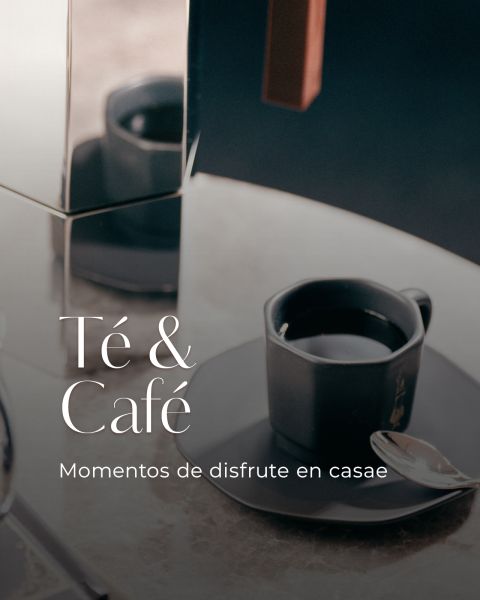 Una taza de café negra y un platillo con una cuchara sobre una mesa, junto a una tetera de metal. El texto dice: "Té & Café. Momentos de disfrute en casae."