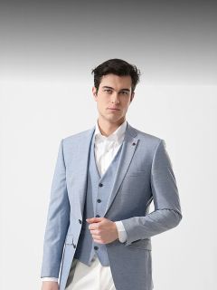 Hombre con traje azul claro y camisa blanca, de pie frente a un fondo blanco liso, mirando a la cámara con confianza.