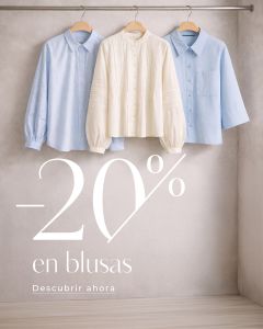 Tres blusas - dos azul claro y una blanca - cuelgan de perchas de madera que anuncian un 20% de descuento en blusas en español.