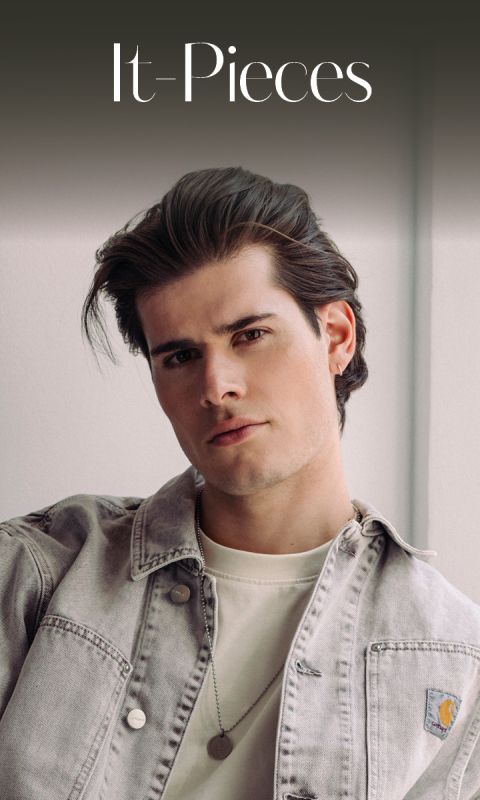 Un joven con el pelo arreglado, que lleva una chaqueta vaquera clara y una camisa blanca y mira a la cámara bajo el texto "It-Pieces".