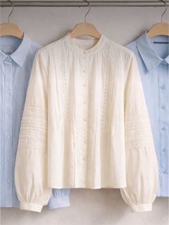 Tres camisas con cuello abotonado en perchas, una camisa blanca texturizada en el centro y dos camisas azul claro a ambos lados.