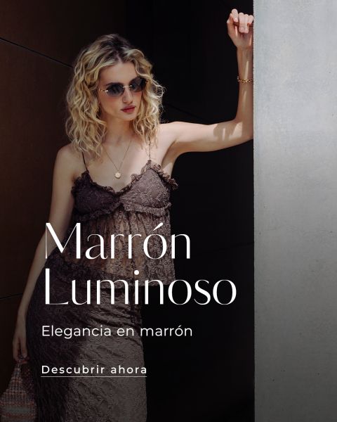 Una mujer con un vestido marrón y gafas de sol está de pie junto a una pared. El texto dice: "Marrón Luminoso, Elegancia en marrón, Descubrir ahora."