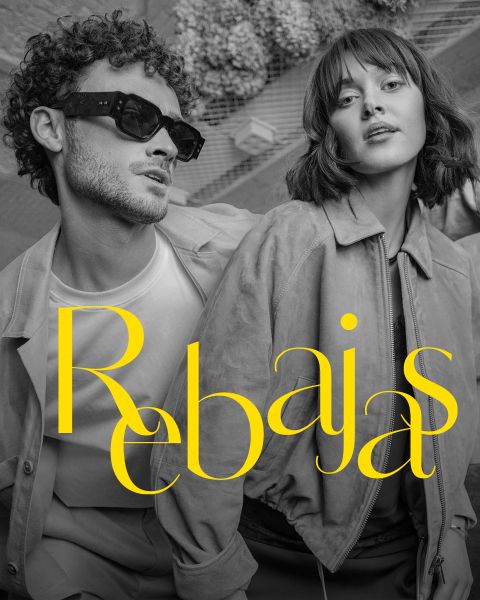 Un hombre y una mujer elegantes posan con atuendos de moda. La palabra "Rebajas" (en español para "rebajas") está escrita en letras amarillas y negritas sobre la imagen.