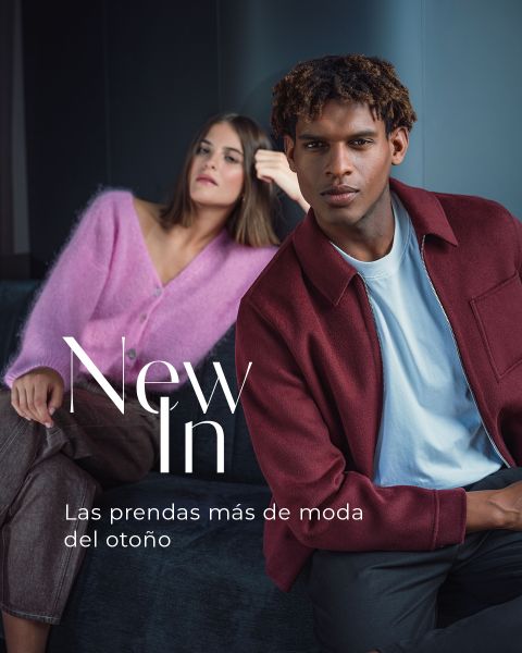 Una mujer con un cárdigan rosa y un hombre con una chaqueta burdeos posan en un sofá; el texto dice: «Recién llegados. Las prendas más de moda del otoño.»