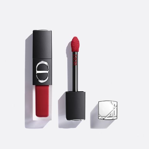 Un labial líquido rojo de Dior, con el aplicador extraído y la tapa plateada a un lado, todo sobre un fondo blanco.