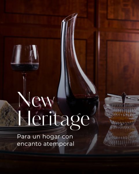 Jarra de vino, una copa de vino tinto, queso y un postre sobre una mesa pulida, junto con el texto "New Heritage. Para un hogar con encanto atemporal.".