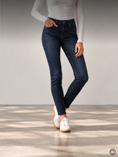 Una persona con una camisa blanca de manga larga, vaqueros ajustados azul oscuro y zapatillas blancas.