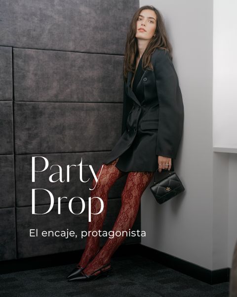 Una mujer con un blazer negro y medias de encaje rojo posa con un bolso negro, sobre el que se superpone el texto "Party Drop: El encaje, protagonista".